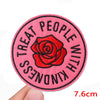 A round pink embroidered patch with the text Treat People With Kindness and a red rose design.