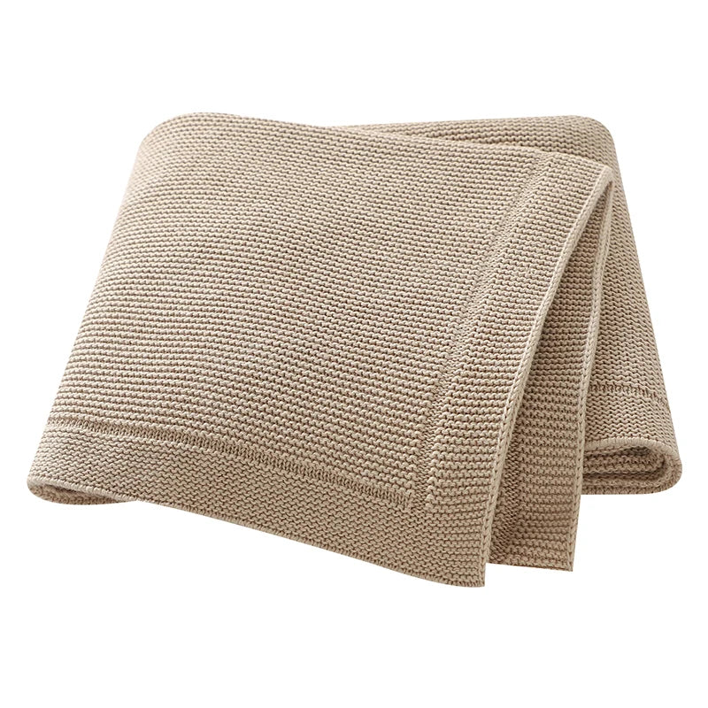 A beige knitted baby swaddle blanket folded and displayed on a white background.