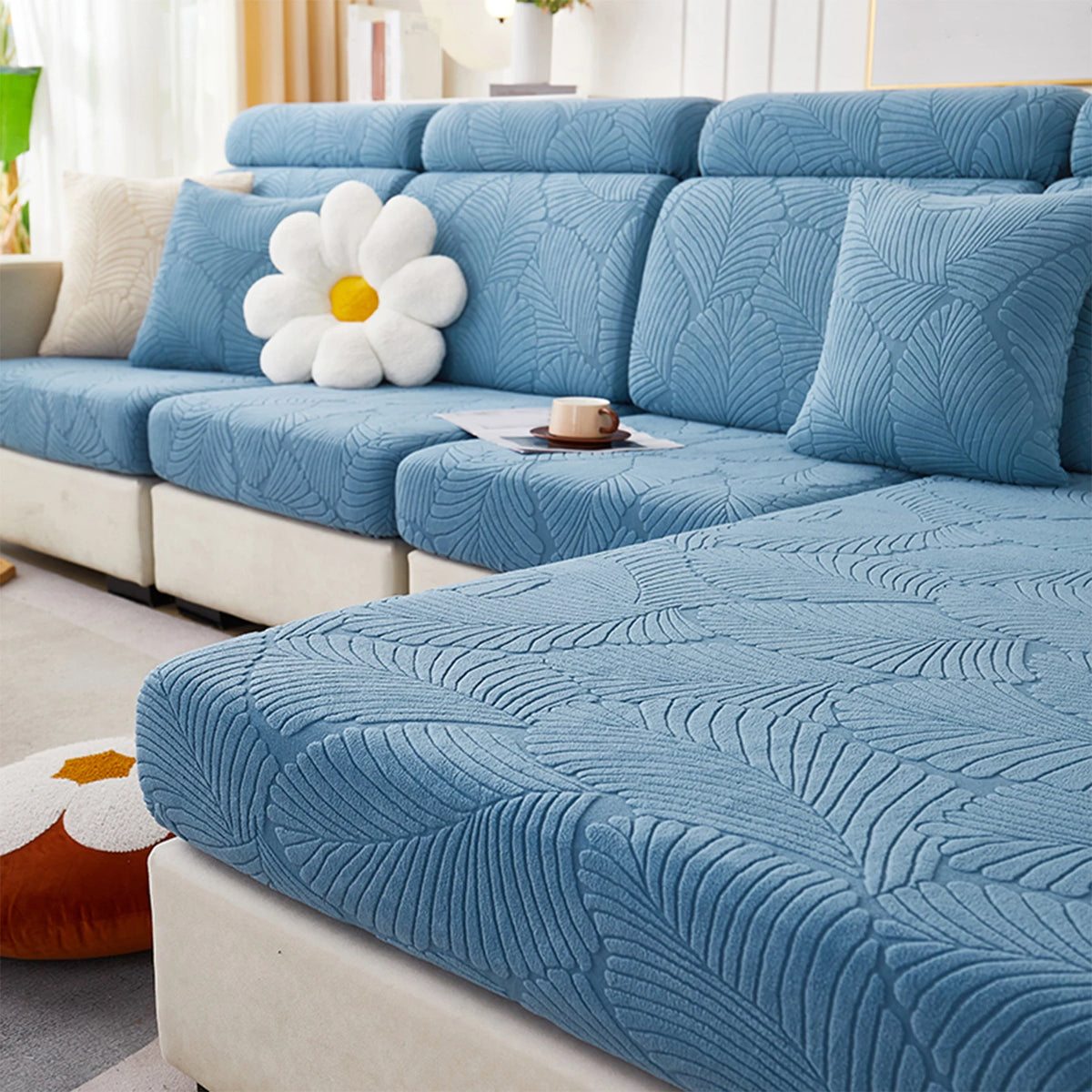 A light blue leaf jacquard stretch sofa cover with anti-slip backing shown on a modern sofa.