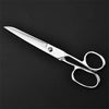 A pair of professional stainless steel sewing scissors lying on a dark surface.