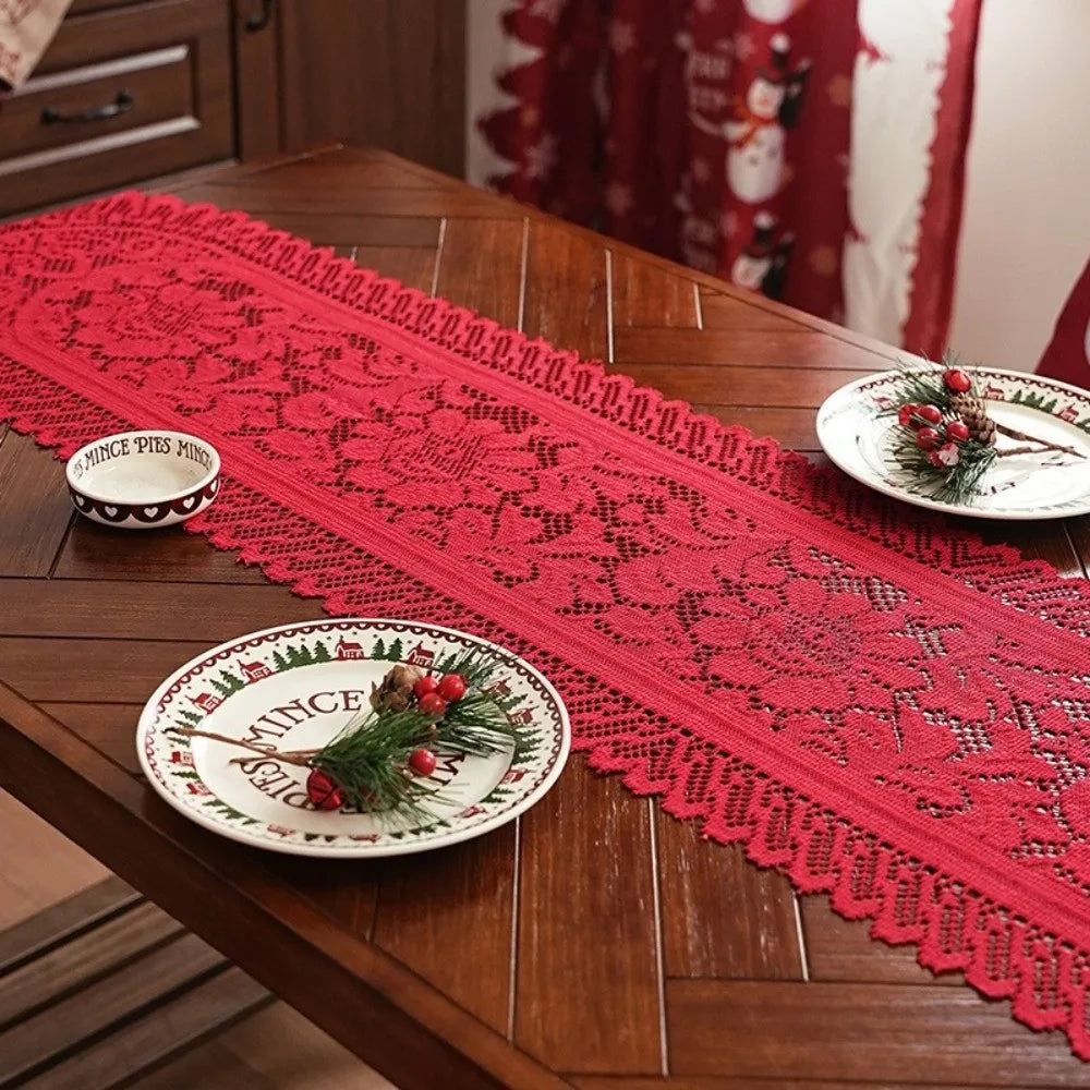 A red lace table runner with intricate patterns and tassels is displayed on a wooden table.