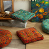 A collection of colorful bohemian cotton linen throw cushions displayed on a wooden shelf and floor.