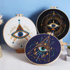 A beginner embroidery starter kit featuring two circular designs of stylized eyes with star patterns on wooden boards.