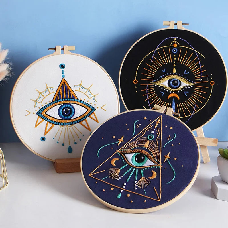 A beginner embroidery starter kit featuring two circular designs of stylized eyes with star patterns on wooden boards.