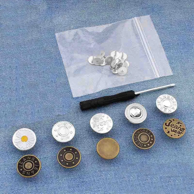 A collection of silver metal button pins is displayed on a translucent plastic sheet against a blue denim background.