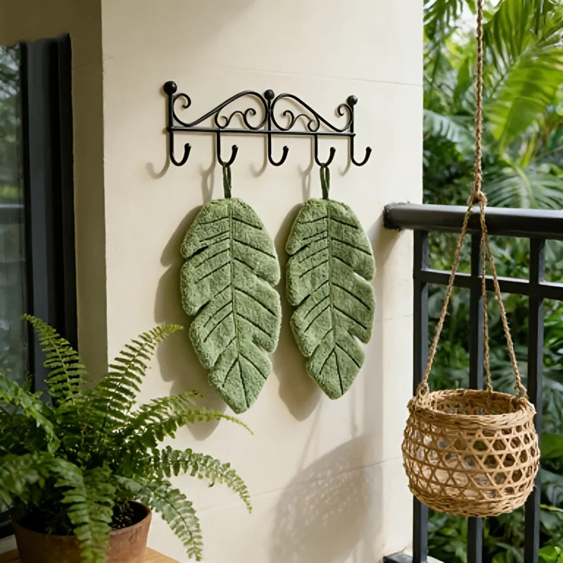 Decorative banana leaf hanging hand towel displayed on a wall with a wrought iron hanger.