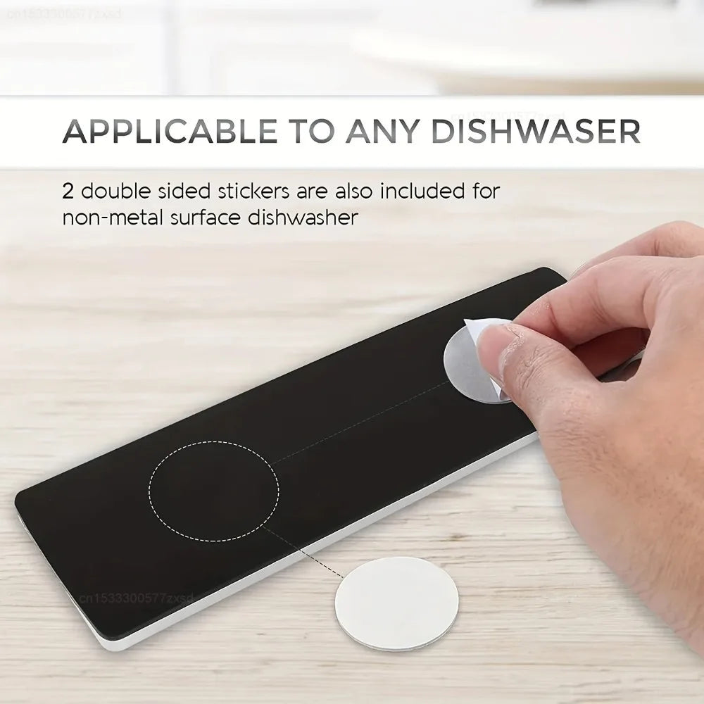 A hand is placing a magnetic dish indicator sticker onto a black surface, demonstrating its use for a dishwasher.