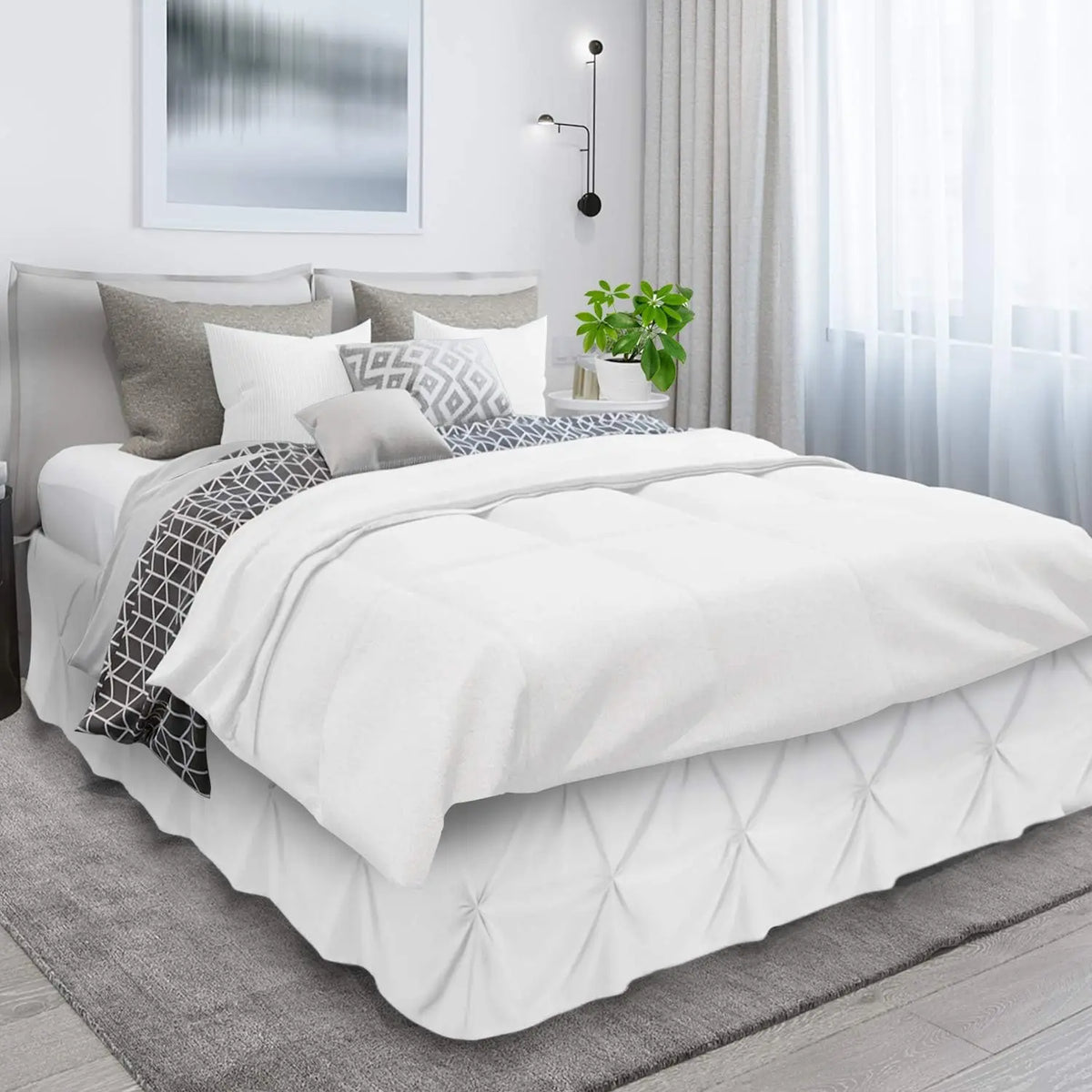 A white duvet and pillows on a bed with a gray headboard and sheer curtains.