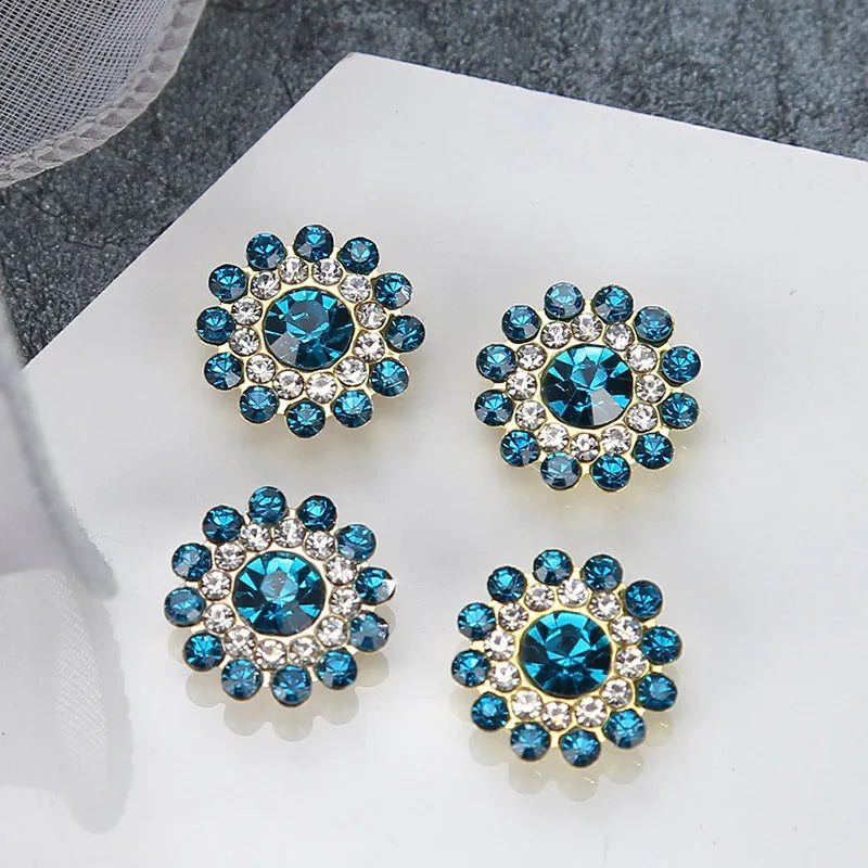 Four clusters of blue and clear rhinestones arranged on a white surface.