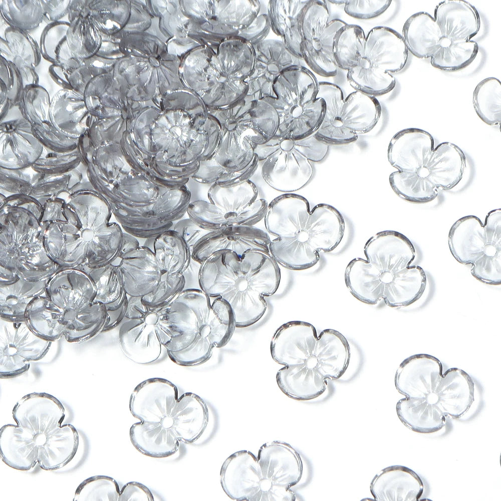 A pile of clear resin flower bead caps for jewelry making.