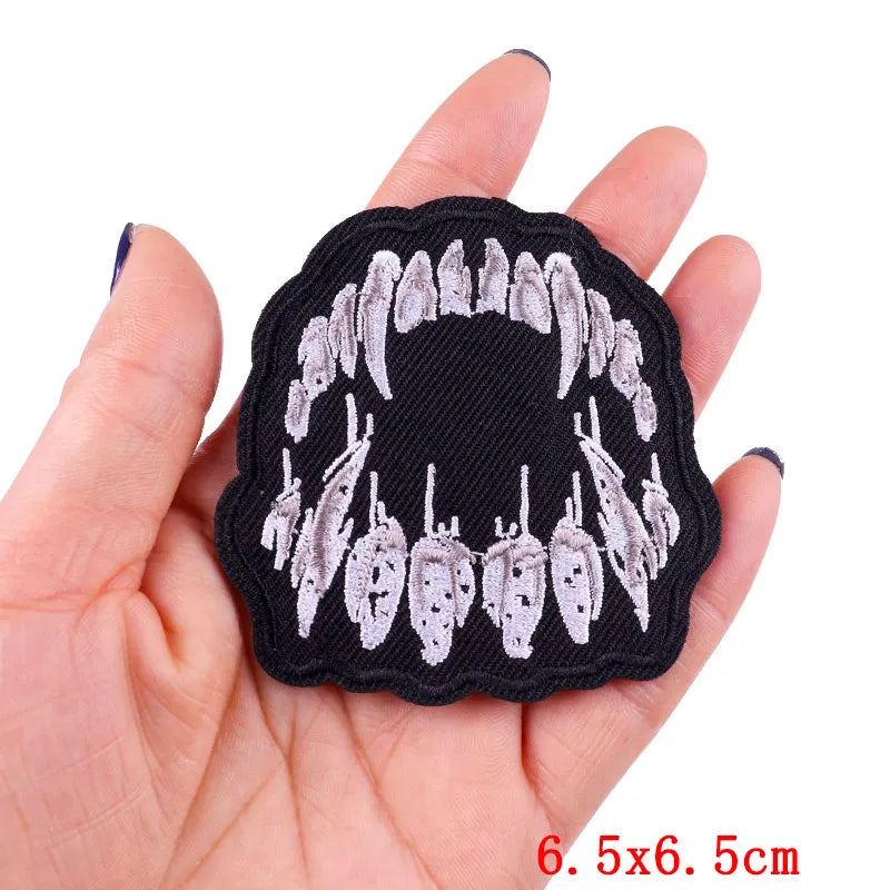 Black embroidery patch featuring a row of white rose skulls on a hand.