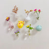 A collection of small ceramic landscape fridge magnets featuring various colors and floral arrangements.