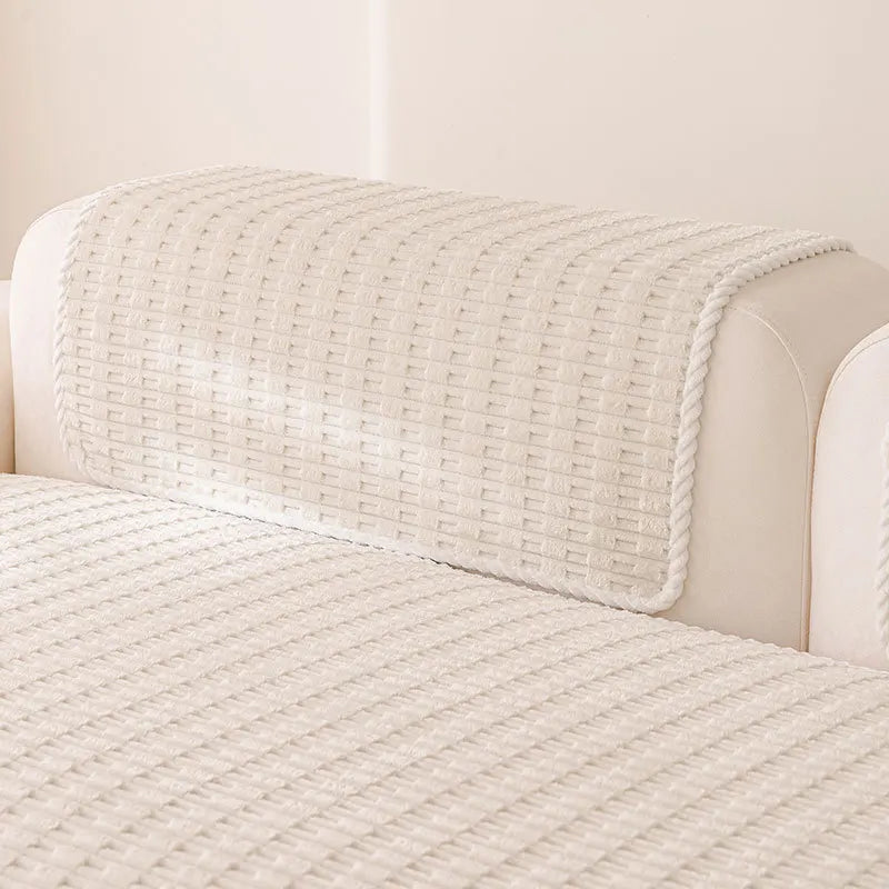 A cream-colored sofa cover with a textured, quilted fabric and a matching fitted throw draped over the back.