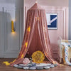 A pink princess hanging bed canopy with gold string lights and a yellow orb on the floor.
