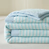 A stack of light blue and white striped luxury jacquard summer quilts.