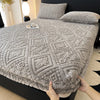 A gray plush jacquard mattress cover is shown on a bed, with a hand holding the fabric.