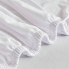 White elastic sofa slipcovers folded and draped on a light surface.