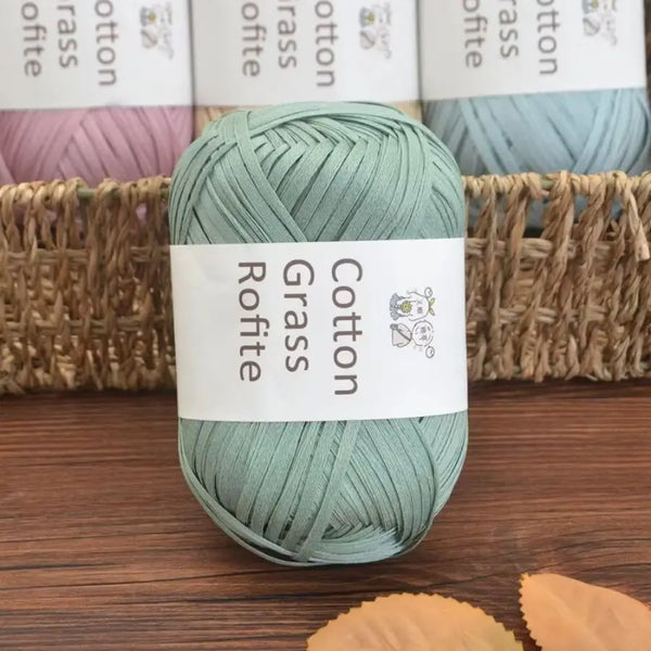 A skein of light green cotton grass yarn resting on a wooden surface next to a woven basket.