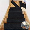 A set of self-adhesive black stair and door mats installed on a light wood staircase.