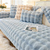 Light blue plush velvet sofa cover with fluffy accent pillows and a white fluffy rug.