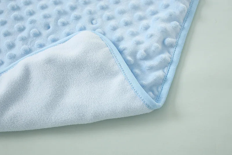 Light blue and white fleece swaddle blanket with a quilted texture shown from the side.