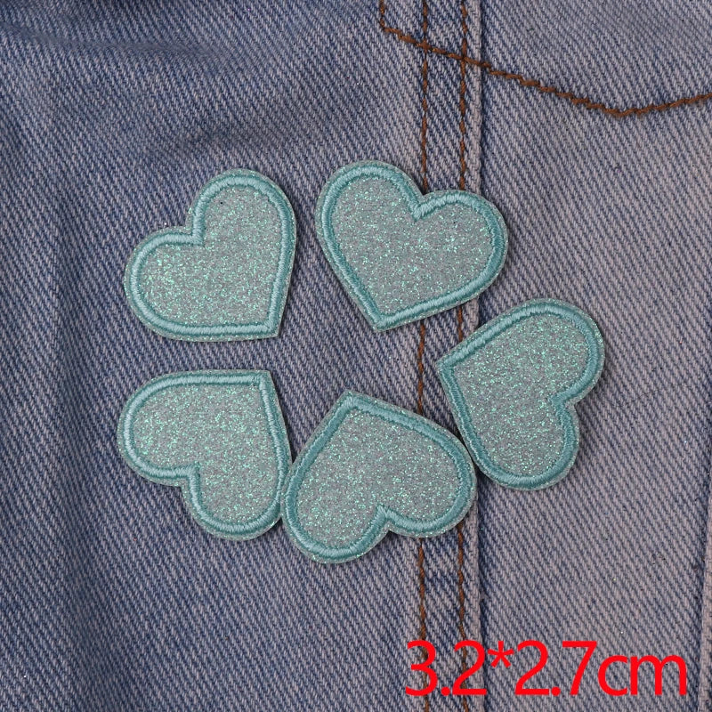 Five glitter iron-on embroidered love heart star patches sewn onto denim fabric.