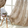 A sheer beige jacquard curtain panel draped over a white chair with a small potted plant.