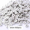 A pile of silver-colored geometric acrylic beads for jewelry making