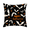 A black pillow featuring a pattern of white bats and orange jack-o'-lanterns for Halloween decoration.