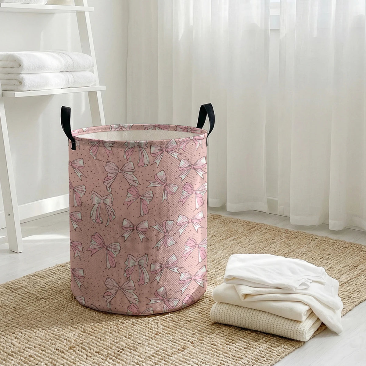 A pink canvas laundry basket with an elegant bow pattern sitting on a woven rug.