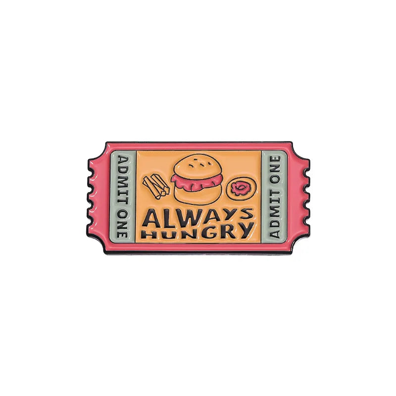 A vintage enamel lapel pin featuring a hamburger and the text ALWAYS HUNGRY on an airline ticket design.