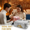 A woman is wrapping a pink gift box for a man in a cozy, knitted sweater indoors.