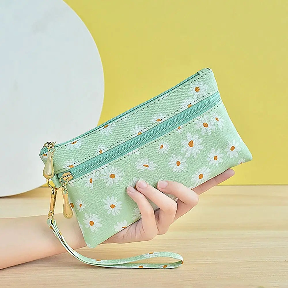 A hand holds a light green PU leather coin purse with a zipper and gold accents against a yellow background.