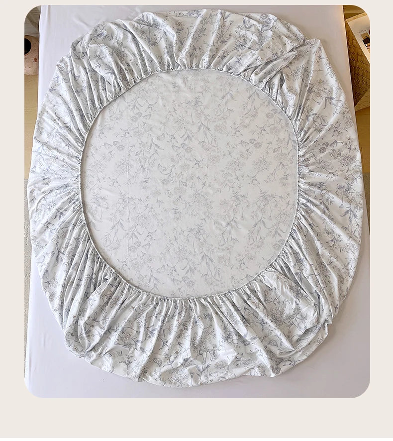 A floral printed cotton fitted sheet with a ruffled edge, suitable for queen or king beds.