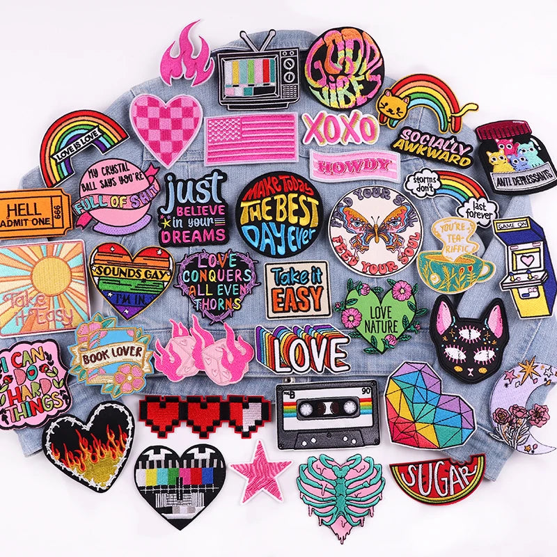 A collection of colorful embroidered letter patches featuring words like LOVE, XOXO, and HOWDY on a gray fabric background.