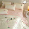 A pink and white embroidered tulip duvet cover set displayed on a bed with matching pillows.