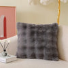 A gray faux fur cushion cover resting on a light-colored sofa.