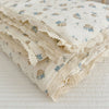 A stack of cream-colored muslin blankets with a blue floral print and delicate lace edges.