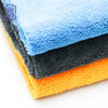 Stack of coral fleece microfiber cleaning cloths in blue, gray, and orange colors.
