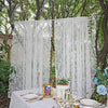 Sheer floral lace window curtains hanging in a garden setting on a white table.