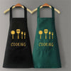A pair of black and green waterproof oil-proof PVC kitchen aprons hanging on a wooden rack.