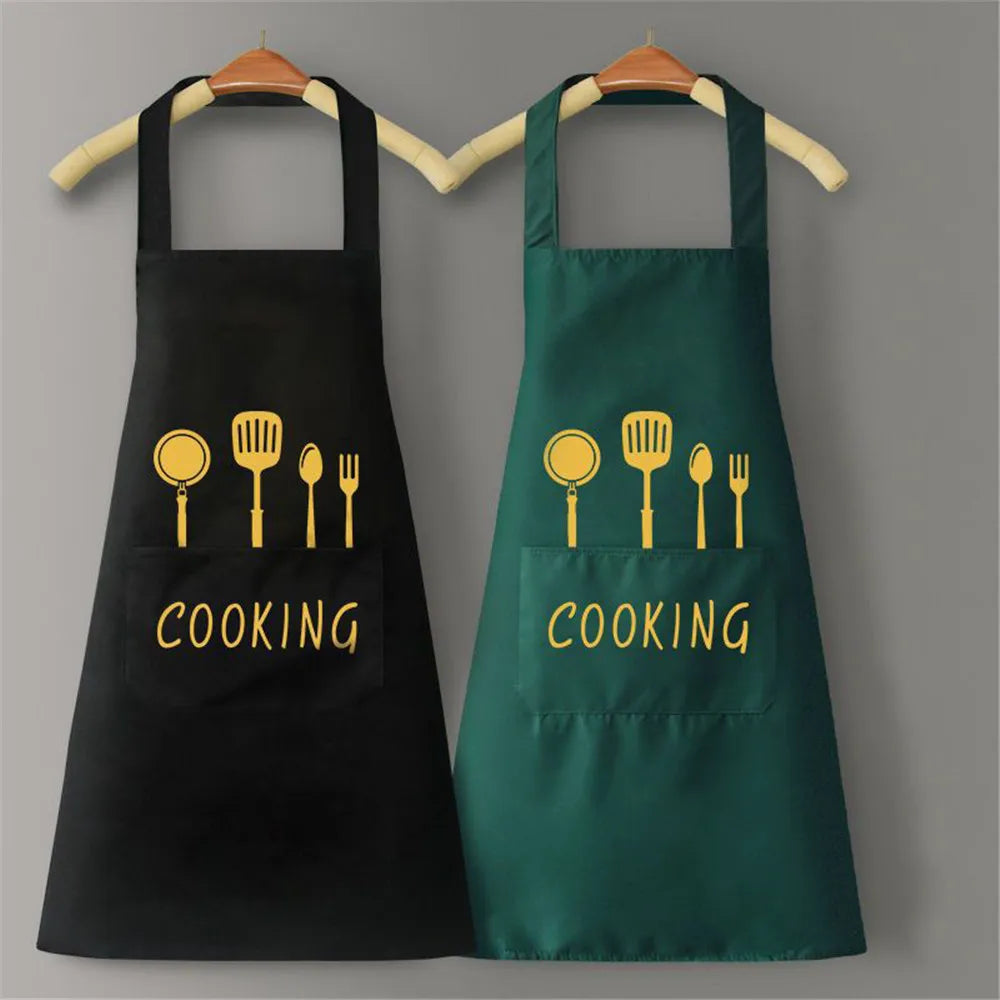 A pair of black and green waterproof oil-proof PVC kitchen aprons hanging on a wooden rack.