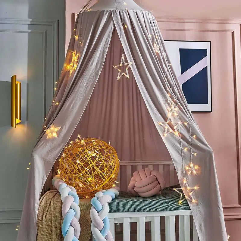 A pink princess hanging bed canopy with sheer fabric and fairy lights, featuring a gold sphere and pink bedding.