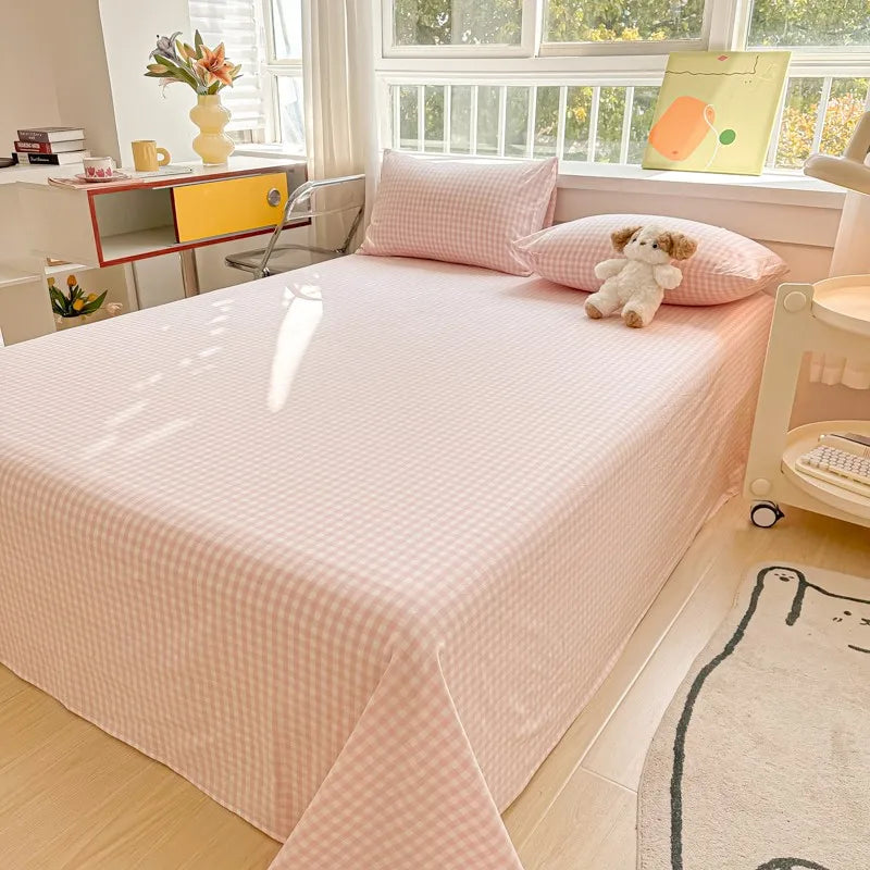 A pink organic cotton bedding set with a quilted flat sheet and pillowcases displayed on a bed.