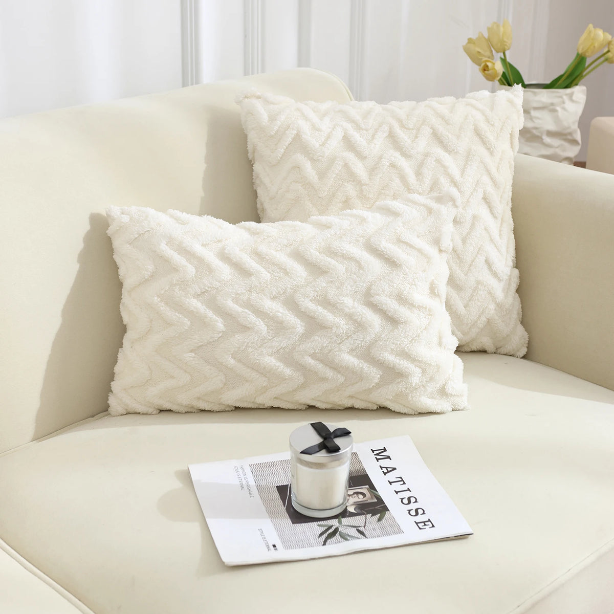 A white, textured geometric plush throw pillow resting on a light-colored sofa.