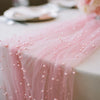 Pink pearl tulle table runner draped elegantly on a white tablecloth.