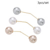 A set of three pearl brooch jewelry items with gold-toned arms.