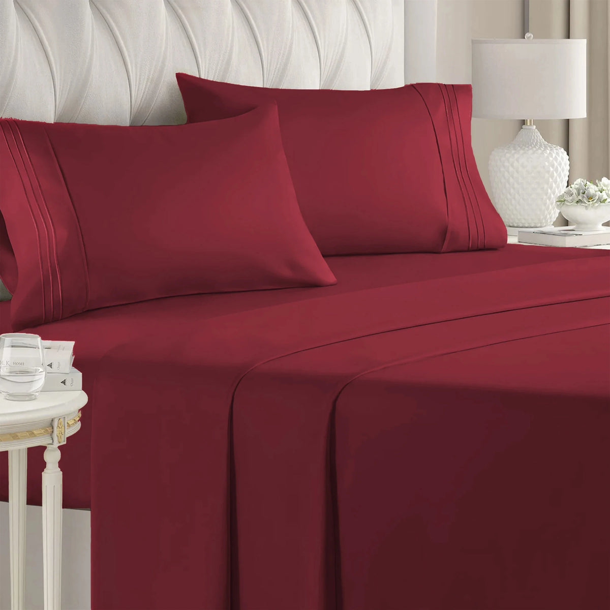A set of deep red microfiber bed sheets with piping and deep pockets on a bed.