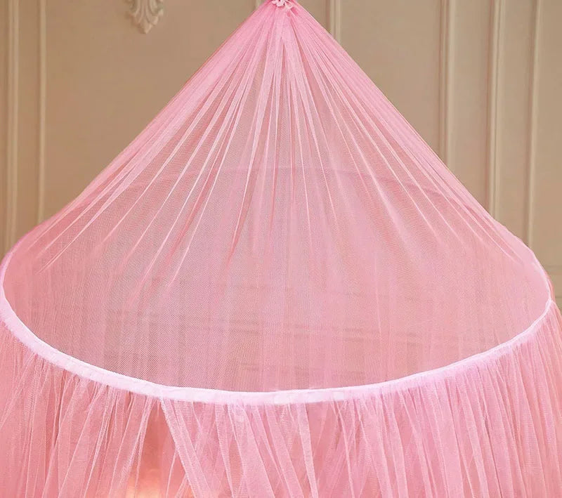Pink sheer dome mosquito net for beds, draped over a light-colored wooden structure.