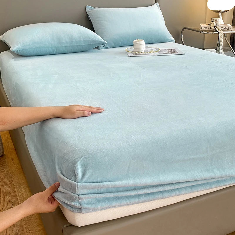 A light blue luxury velvet bedding set featuring a sheet and pillow, shown on a bed.
